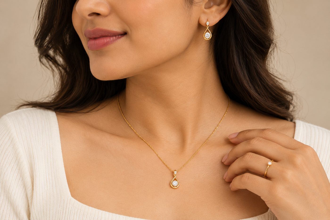 A close crop of a model wearing a gold pendant necklace, gold drop earrings and a thin gold ring